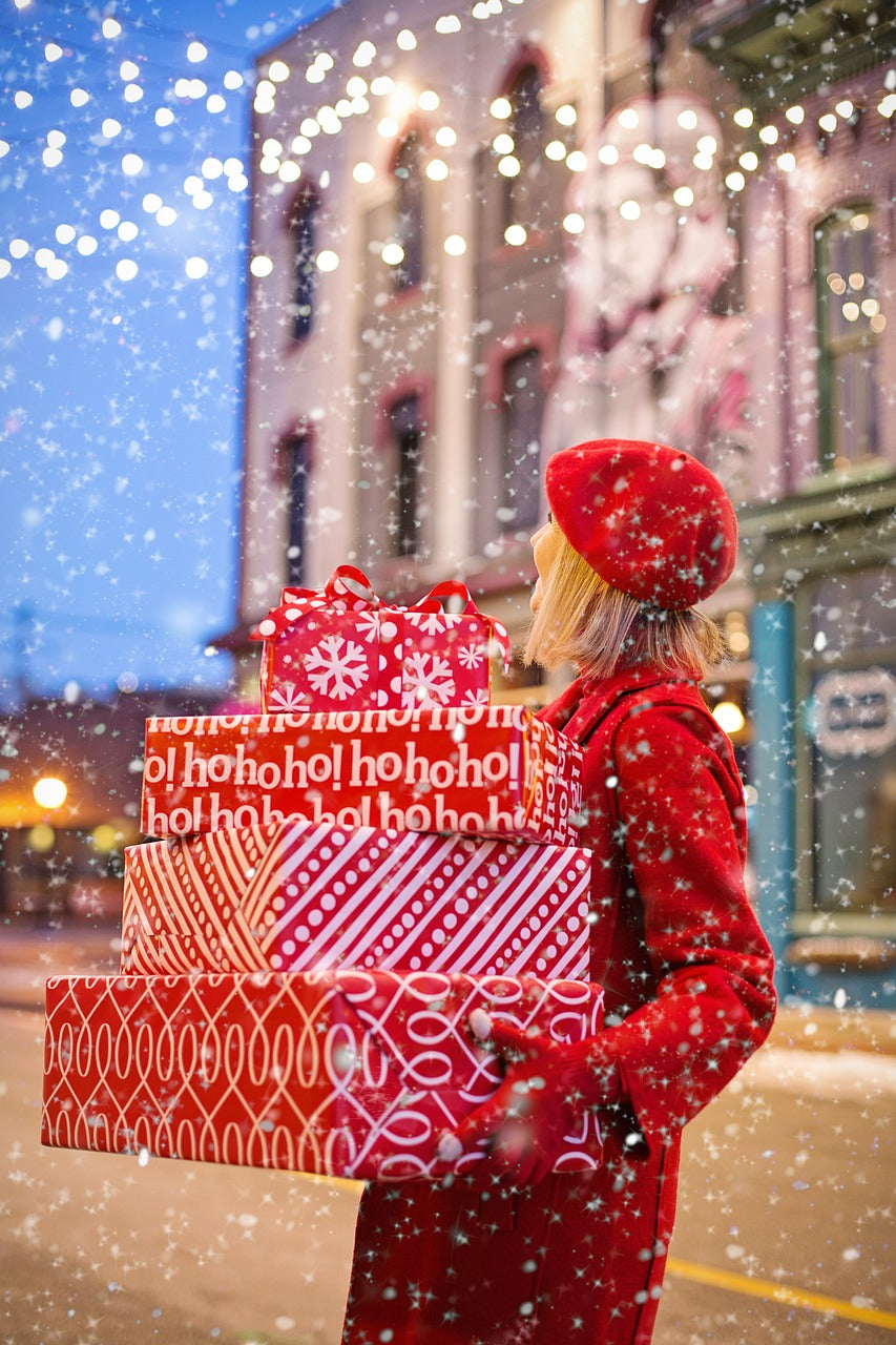 Image by Jill Wellington from Pixabay--a woman carrying holiday presents